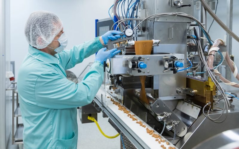 Pharmaceutical technician in sterile environment working with equipment at pharmacy industry